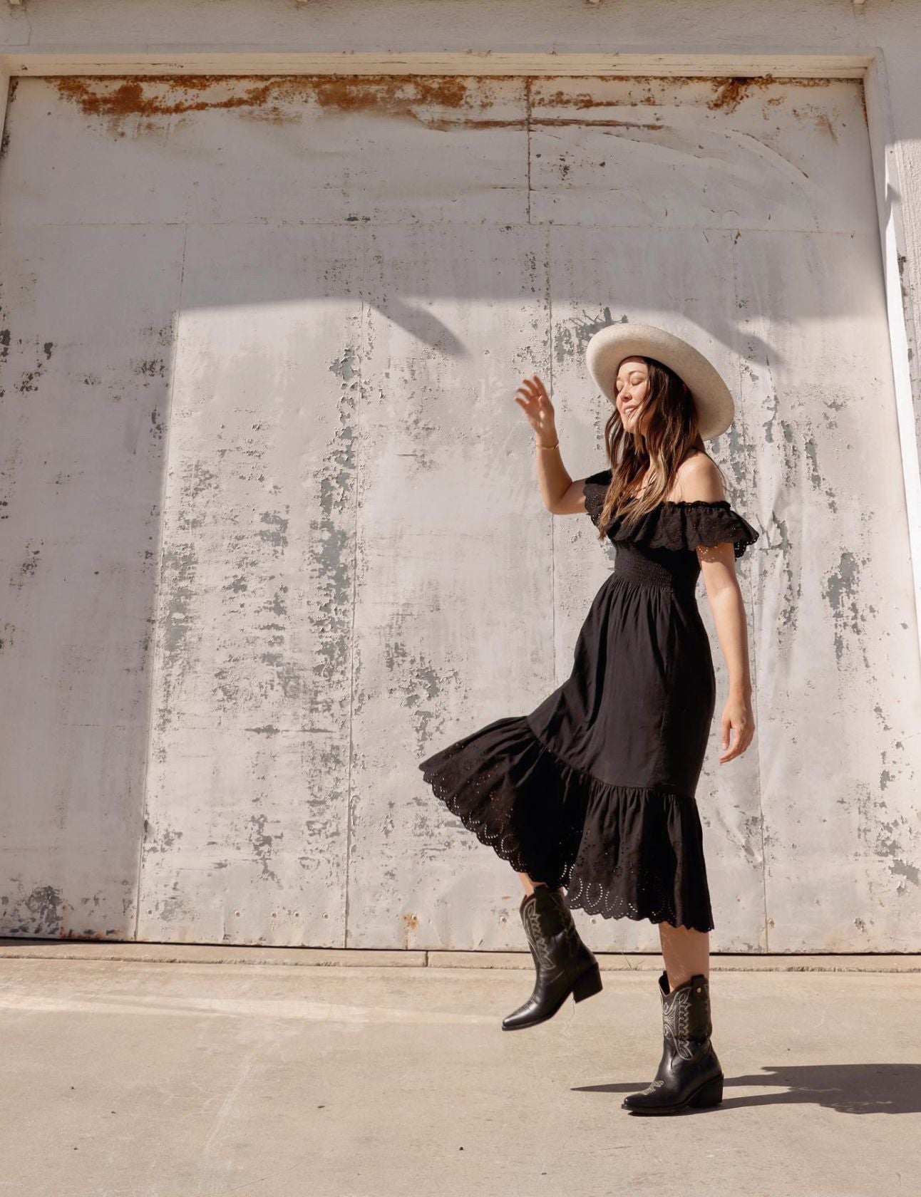 women wearing black leather unstoppable cowboy boots with black maxi dress outdoors 